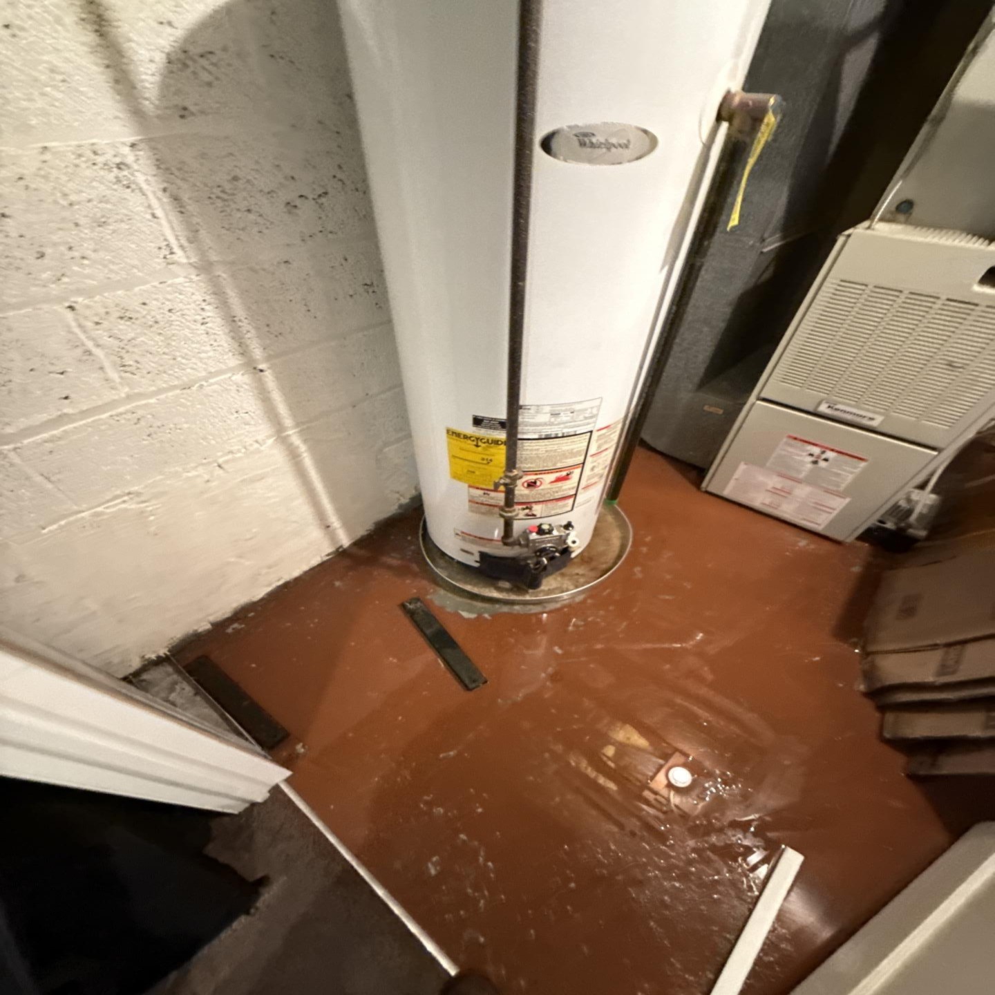 Failed water heater with water across a basement floor during cleanup in New Jersey