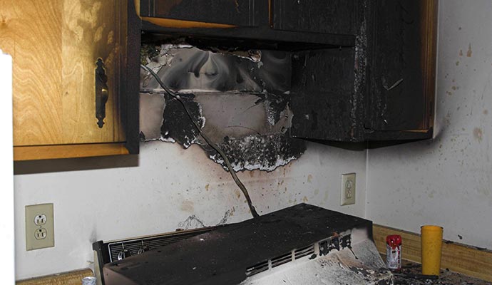 Kitchen cabinet and table visibly damaged by fire